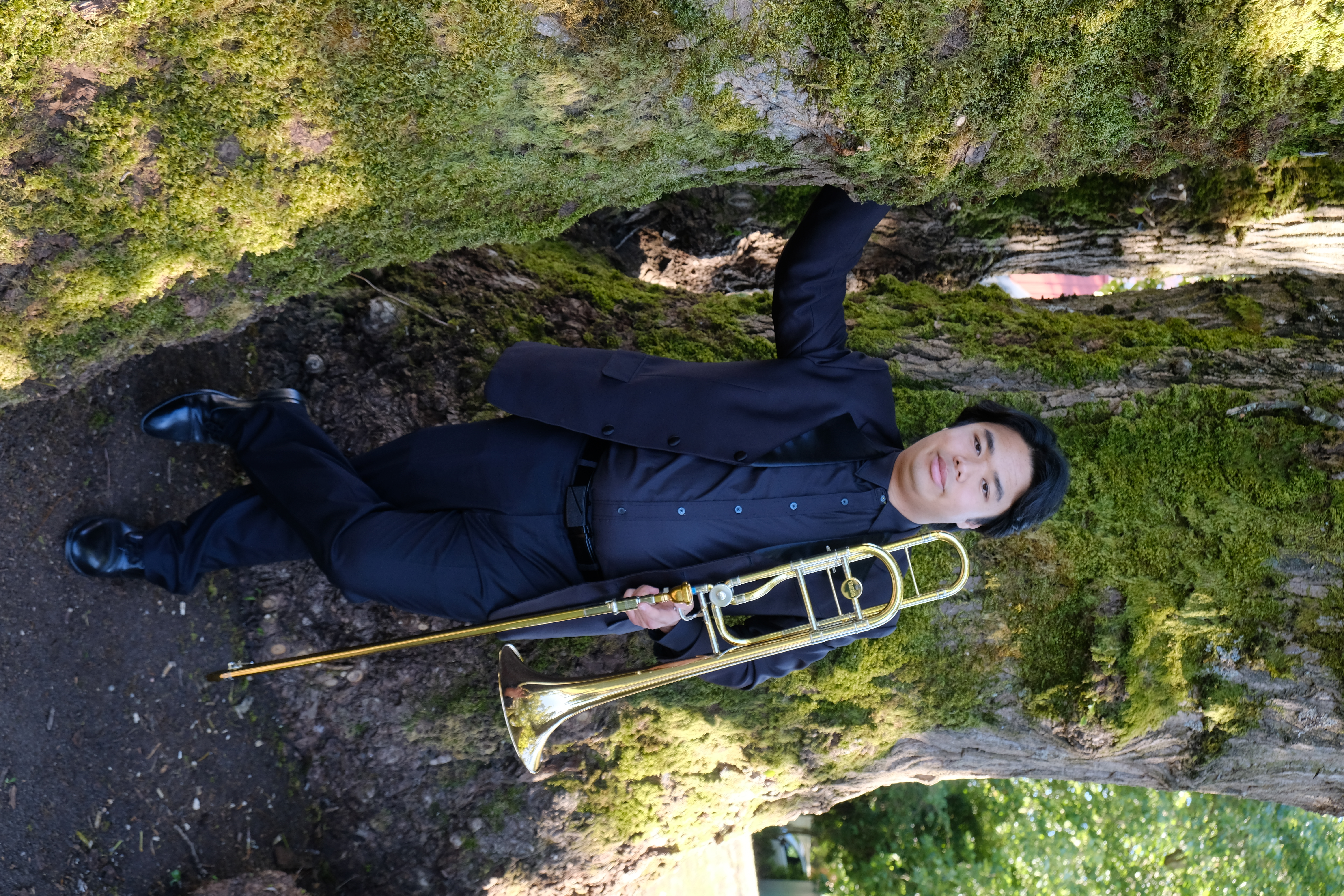 Jobert leaning on tree with trombone.
