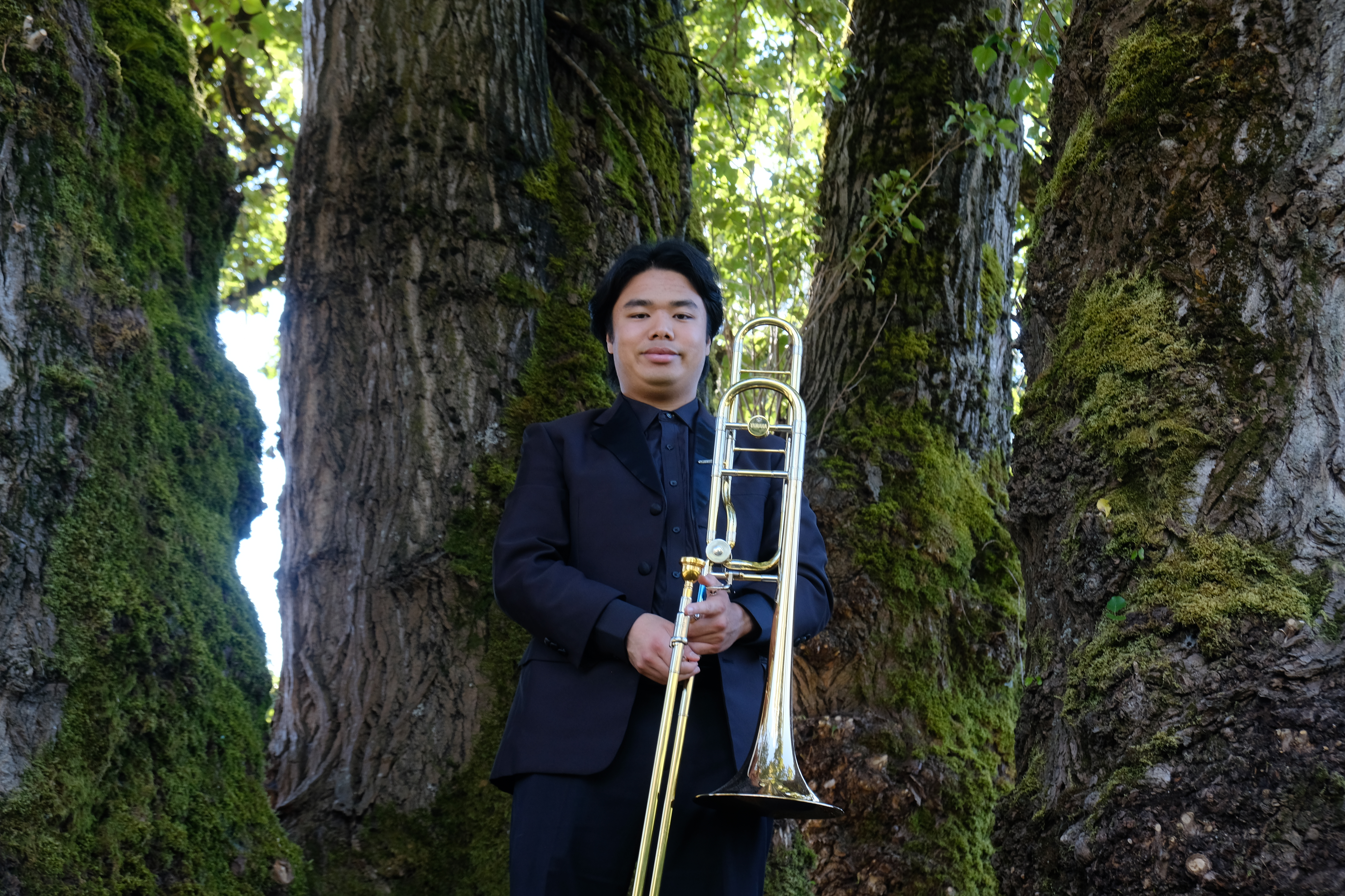 Jobert with trombone in the middle of trees.